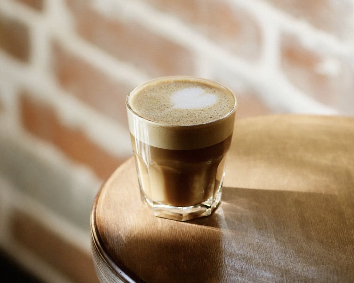 Coffee in a glass near the edge of a table.